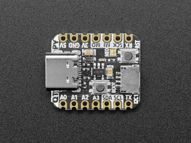 The QT Py RP2040 from above: a small black board with a USB-C connector at the left, two buttons, and pads labelled 5V, GND, 3V, MO, MI, SCK and RX along the top and A0, A1, A2, A3, SDA, SCL and TX along the bottom.