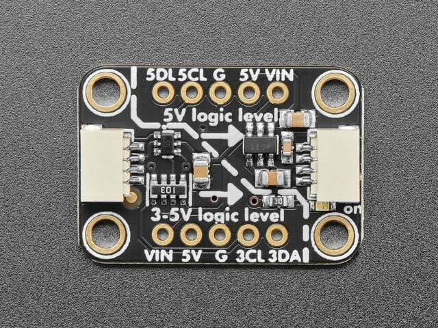 The level booster from the front: a small black board with a STEMMA QT connector at each end, one side marked "5V logic level" with pins 5DA, 5CL, G, 5V and VIN, the other marked "3-5V logic level" with pins VIN, 5V, G, 3CL and 3DA, and arrows pointing from the 3-5V side to the 5V side.